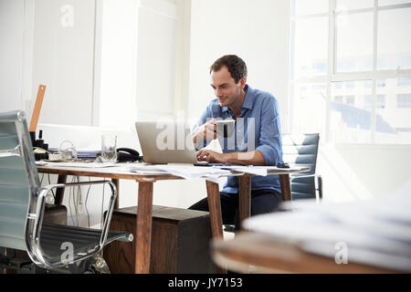 Young businessman using laptop computer and drinking coffee Stock Photo