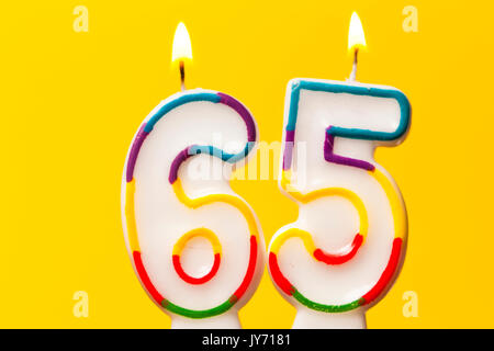 Number 65 birthday celebration candle against a bright yellow background Stock Photo