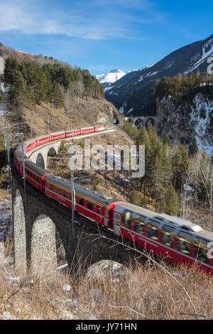 Filisur, Switzerland. The red train running away on the viaduct. Stock Photo