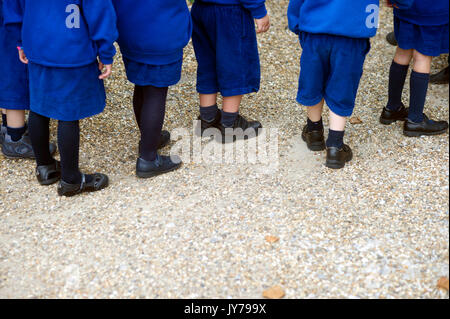 Happy young private school children lining up in school yard Stock Photo