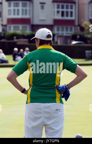 Woman lawn bowls player standing with hands on hips, rear view Stock Photo