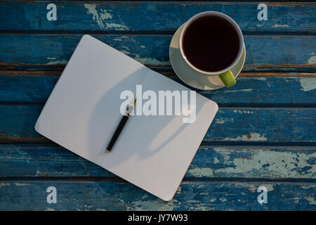 Overhead view of open book by tea cup on wooden table Stock Photo