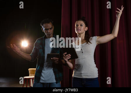 Actors rehearsing on stage while using digital tablet in theatre Stock Photo