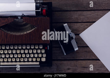 Overhead of vintage typewriter and camera on wooden table Stock Photo