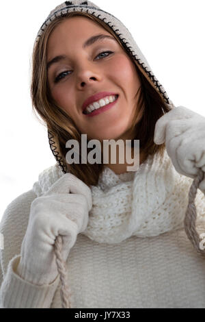 Portrait of smiling woman holding knit hat while standing against white background Stock Photo