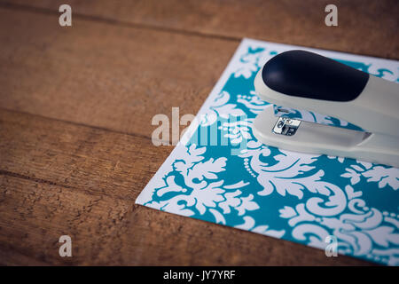 Close up of stapler on patterned paper at table Stock Photo