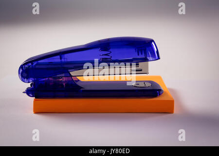 Close-up of stapler on sticky note on white background Stock Photo