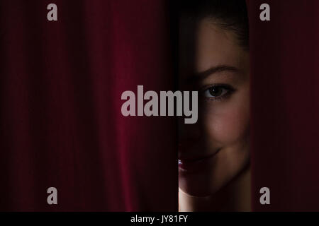 Happy ballet dancer peeking through a stage curtain Stock Photo