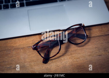 Close up of eyeglasses by laptop on wooden table Stock Photo