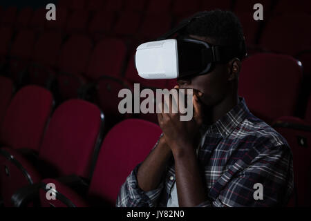 Man using virtual reality headset while watching movie in theatre Stock Photo