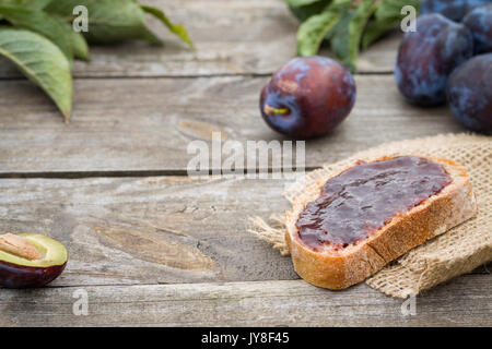 Sandwich with plum jam on old wooden table in garden. Stock Photo