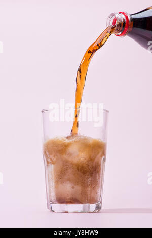 Pouring cola from bottle into glass with splashing Stock Photo