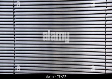gray metal blinds behind a window, horizontal slats of metal, awnings, window shade Stock Photo