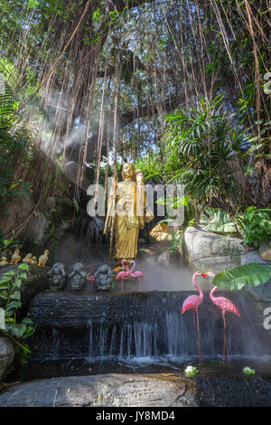 Golden Buddha statue in the tropical garden with waterfall in Wat Saket Golden Mountain Temple, Bangkok, Thailand Stock Photo