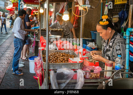 Street food vendors selling warm golden chestnuts in Chinatown markets, Bangkok, Thailand Stock Photo