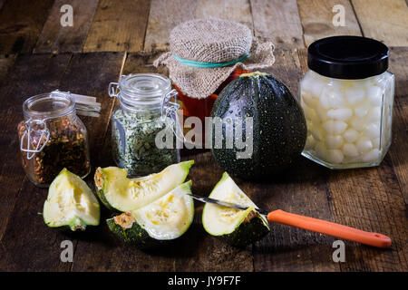 Pumpkin jars and spices. Preparations from your own garden. Wooden kitchen table. Black background. Stock Photo