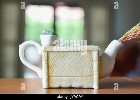 Decorative kettle on a wooden desk and living room background Stock Photo