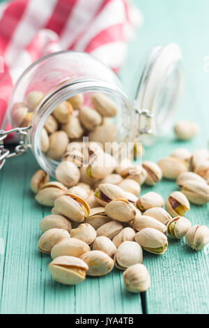 Dried pistachio nuts in jar on kitchen table. Pistachio kernel. Stock Photo
