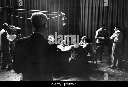 American television host Lynn Poole (near, back turned to camera) and cast on set for 'Troubled People Meet' segment of the Johns Hopkins Review television program, 1951. Stock Photo