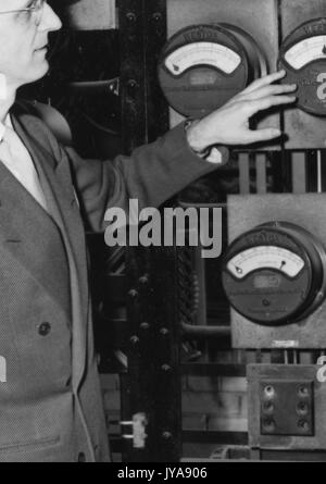 American television host Lynn Poole on set of the Johns Hopkins Science review television program looking at an analog gauge, 1951. Stock Photo