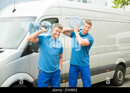 Two Delivery Men In Front Of Cargo Van Delivering Bottles Of Water Stock Photo