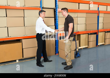 Happy Manager Shaking Hands With Worker In Warehouse Stock Photo