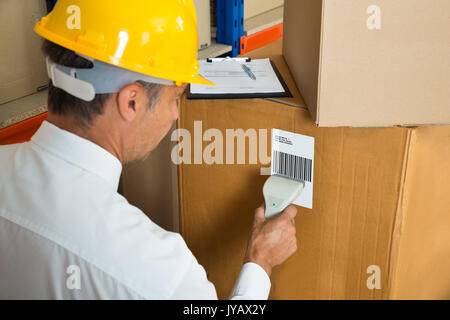 Manager Scanning Label On Cardboard Box With Barcode Scanner In Warehouse Stock Photo