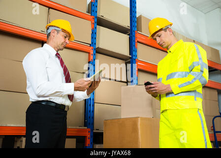 Warehouse Worker Checking The Inventory With Manager In A Large Warehouse Stock Photo