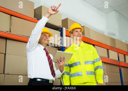 Warehouse Worker And Manager Checking The Inventory In A Large Warehouse Stock Photo
