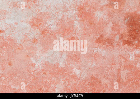 Close-up of a weathered and aged concrete wall, bleached red paint partly peeled off. Texture background. Stock Photo