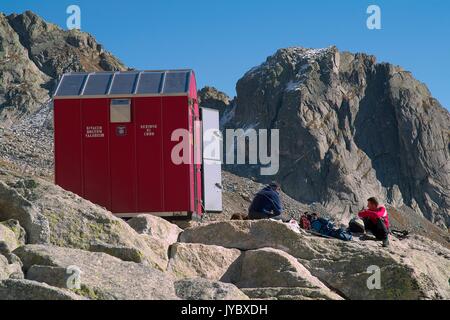 Hikers resting at the entrance of the bivouac Molteni Valsecchi makeshift shelter for trekkers who venture on these  peaks. Valmasino. Valtellina. Lom Stock Photo