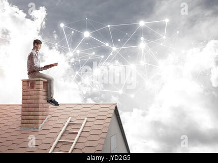 Man on brick roof reading book and concept of social connection Stock Photo
