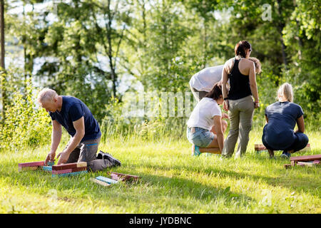 Mature Man And Friends Playing With Building Blocks On Field Stock Photo