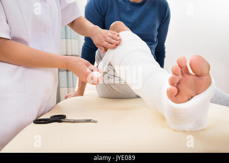 Close-up Of A Female Doctor Bandaging Patient's Leg Stock Photo