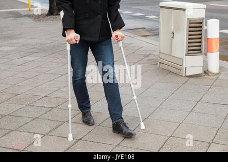 Man Trying To Walk On Street With The Help Crutches Stock Photo