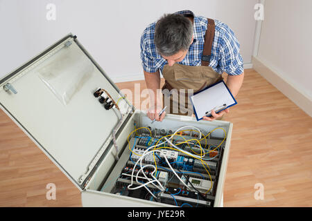 Electrician Looking At Fuse Box Holding Clipboard Stock Photo