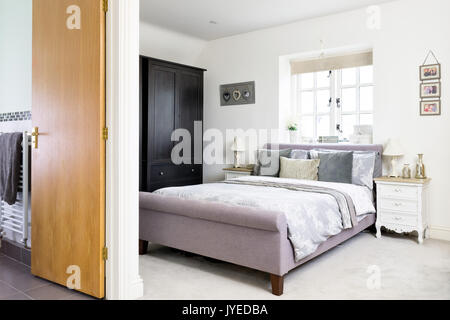 A king sized bed in a  modern double bedroom with en-suite facilities. Stock Photo