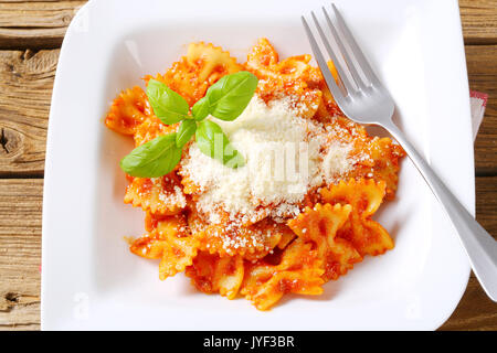 Bow-tie pasta with tomato sauce and parmesan Stock Photo