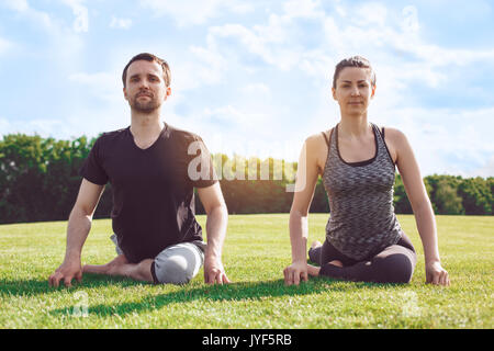Man and woman practice acro yoga in the park stretching Stock Photo
