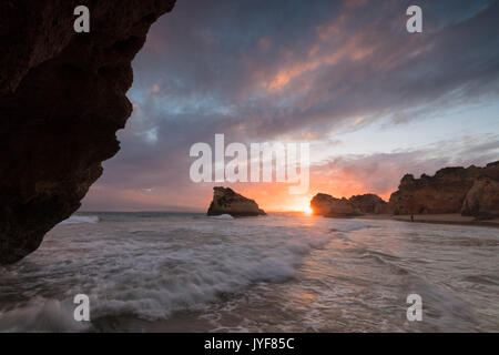 Clouds frame the rough sea and cliffs at sunset Praia Dos Tres Irmaos Portimao Algarve Portugal Europe Stock Photo