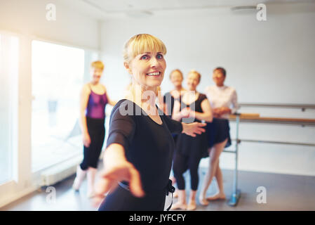 Happy mature woman dancing in a ballet studio with a group of friends in the background Stock Photo