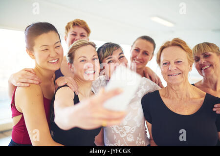Mixed age group of laughing women standing arm in arm taking a selfie tgether in a dance studio Stock Photo