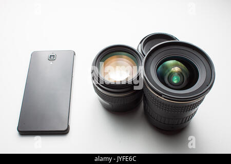 close-up of group of camera lenses and a mobile phone on a white background Stock Photo