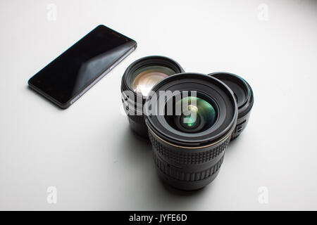 close-up of group of camera lenses and a mobile phone on a white background Stock Photo