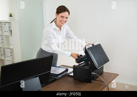 Young Happy Businesswoman Holding Laser Cartridge With Printer At Desk Stock Photo