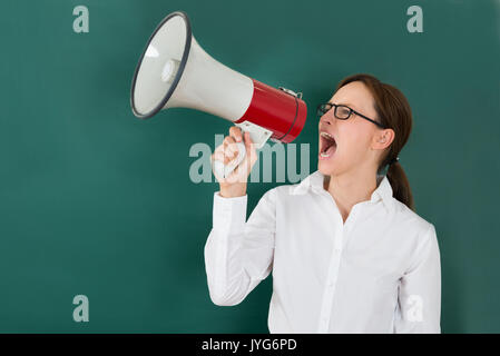 Young Businesswoman Shouting Though Megaphone Against Chalkboard Stock Photo