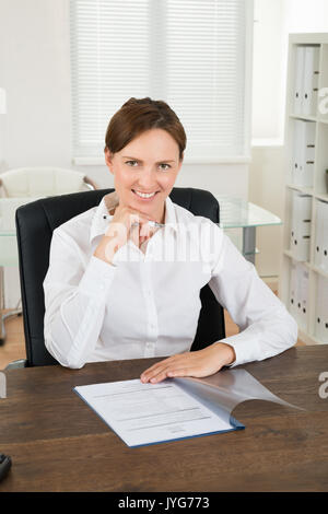 Happy Businesswoman Writing On Document In Office Stock Photo