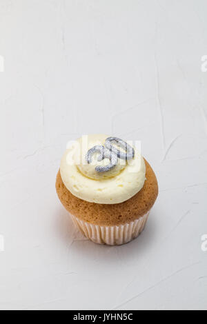Single vanilla sponge cup cake with silver glitter number 30 on top of creamy white frosting isolated on rustic white background - celebration backgro Stock Photo