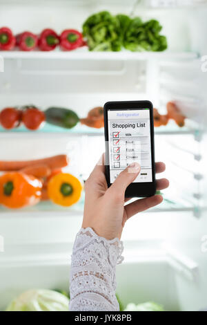 Close-up Of Person Hand With Mobile Phone Showing Shopping List On Display Stock Photo