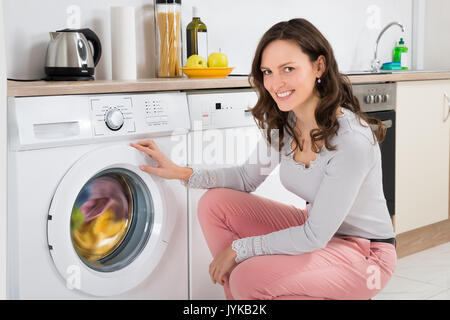 Young Happy Woman Cleaning Multi-colored Clothes In Washing Machine At Home Stock Photo